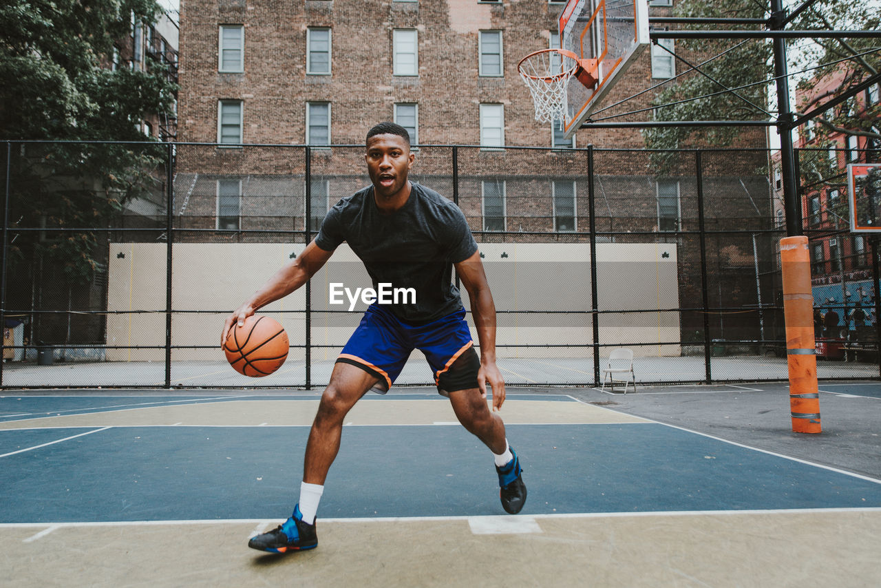 Young man practicing basketball in court