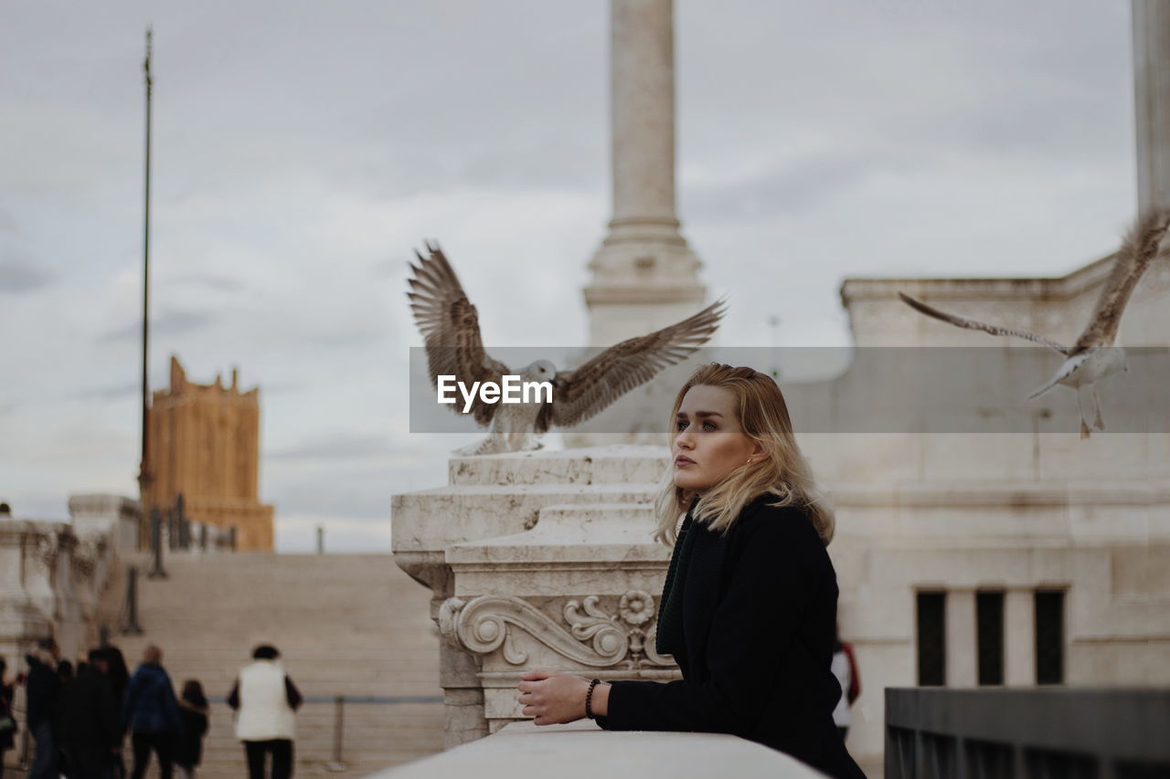 Young woman looking away while standing by railing