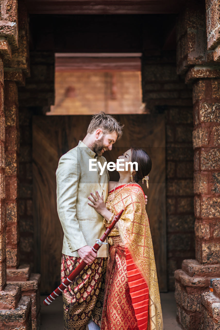 Couple holding hands while standing against building