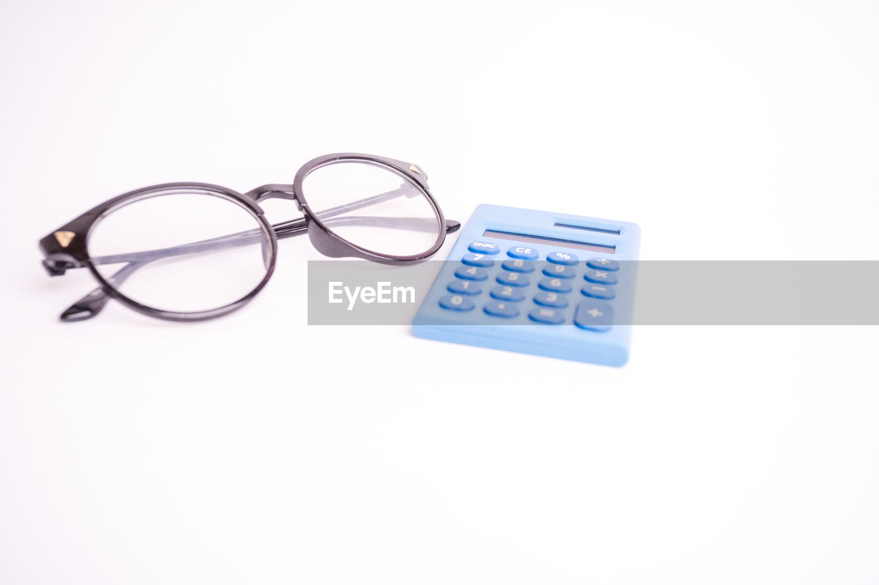 HIGH ANGLE VIEW OF EYEGLASSES ON PAPER AGAINST WHITE BACKGROUND