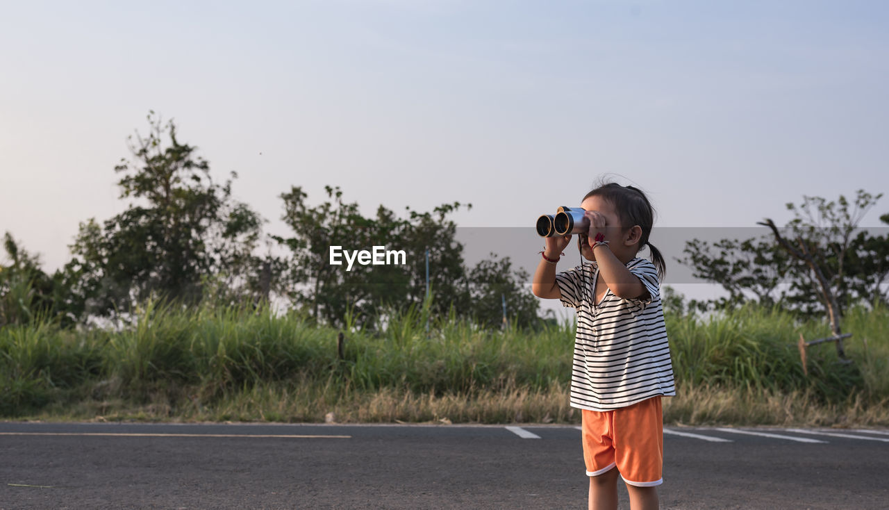 rear view of young woman standing on road against sky