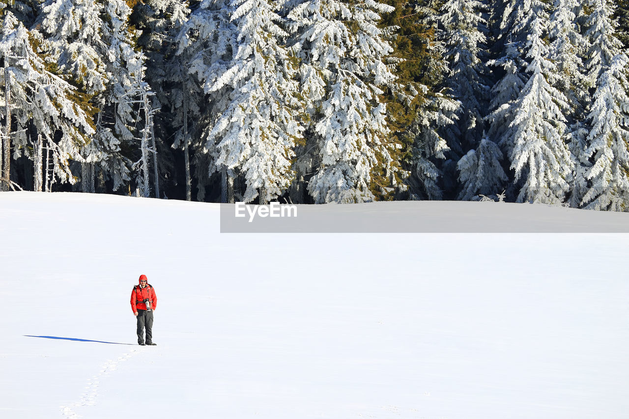 MAN WITH UMBRELLA STANDING ON SNOW