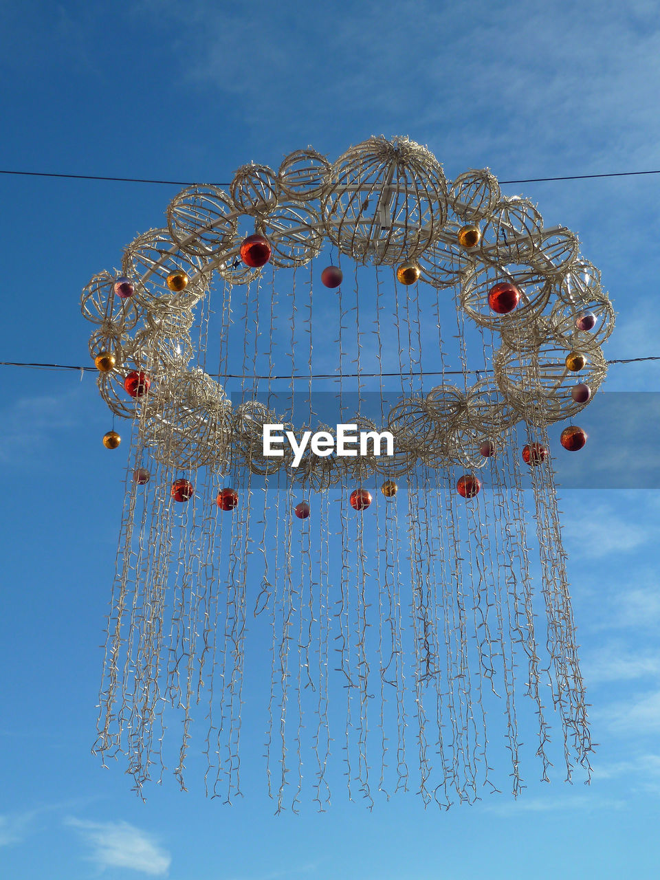 Low angle view of christmas decoration hanging against blue sky