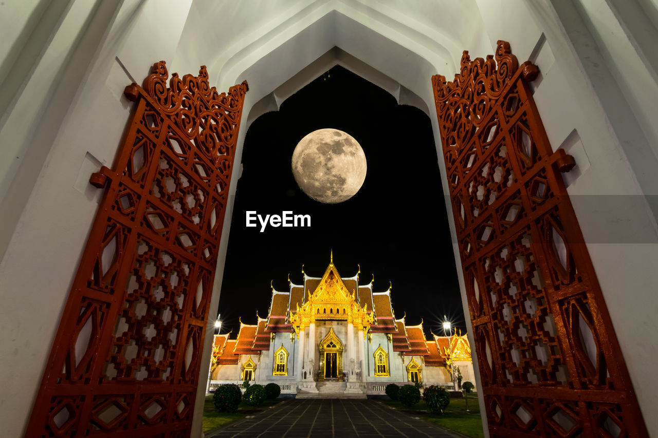 LOW ANGLE VIEW OF ILLUMINATED TEMPLE AND BUILDING