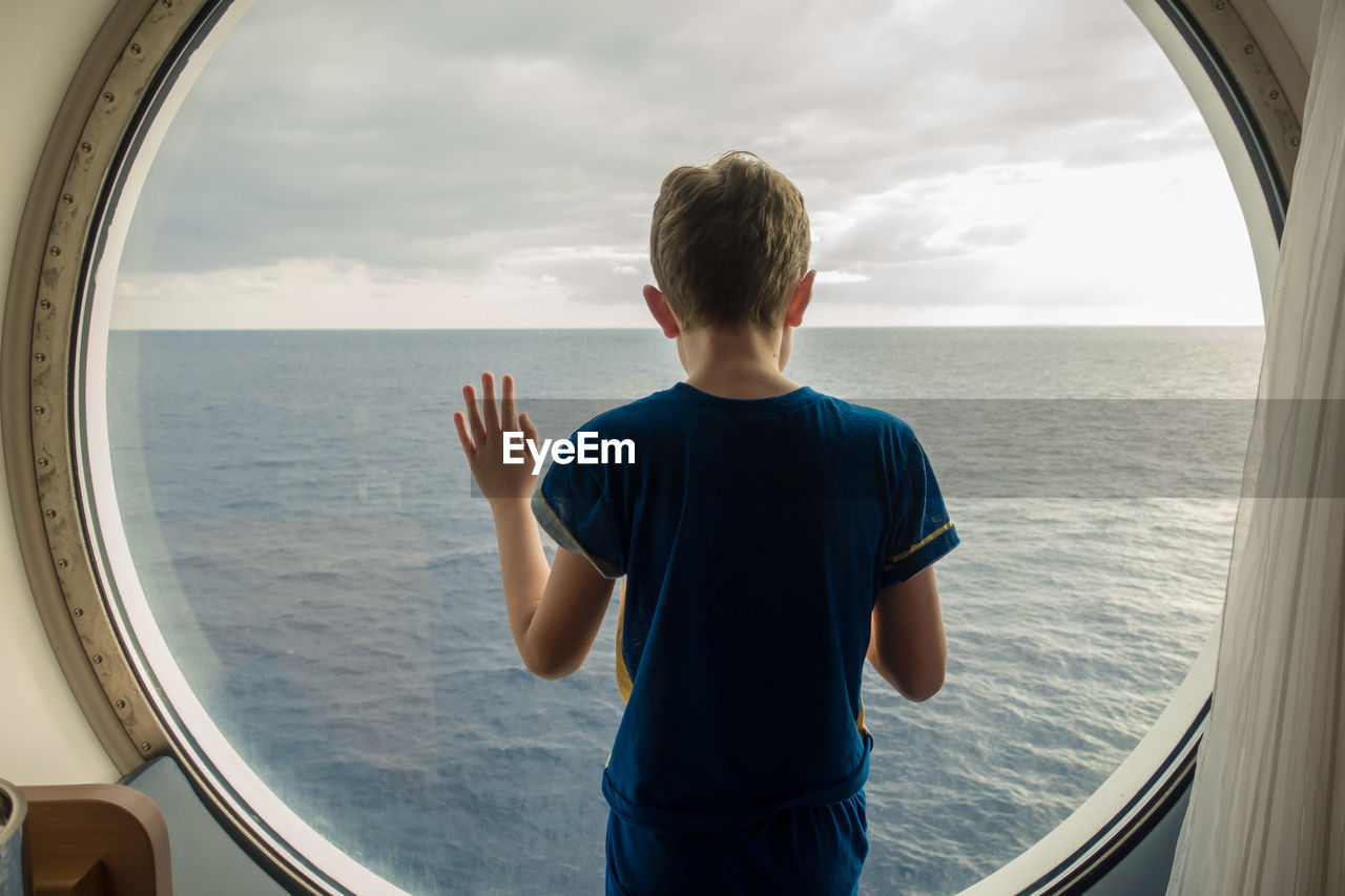 Boy looking at sea against sky