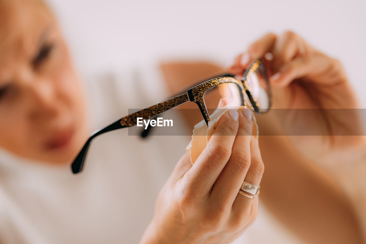 Woman with ocd or obsessive compulsive disorder. cleaning her eyeglasses.