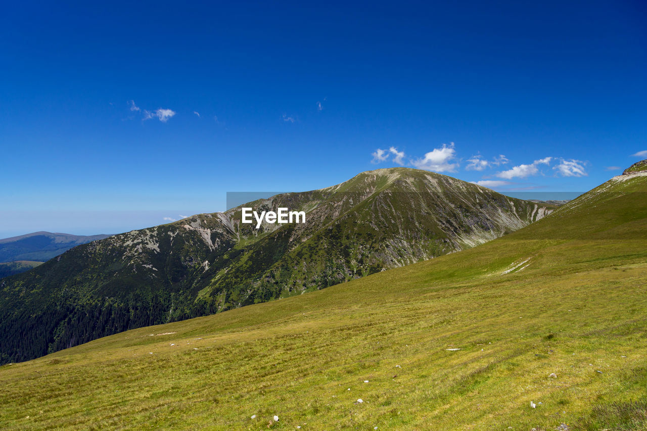 Scenic view of mountains against blue sky