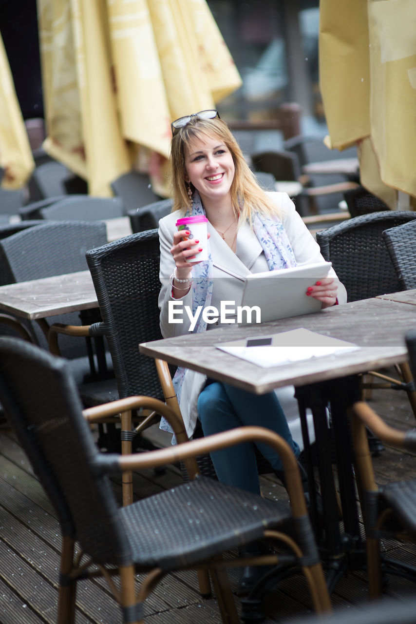 Smiling young woman having drink at table