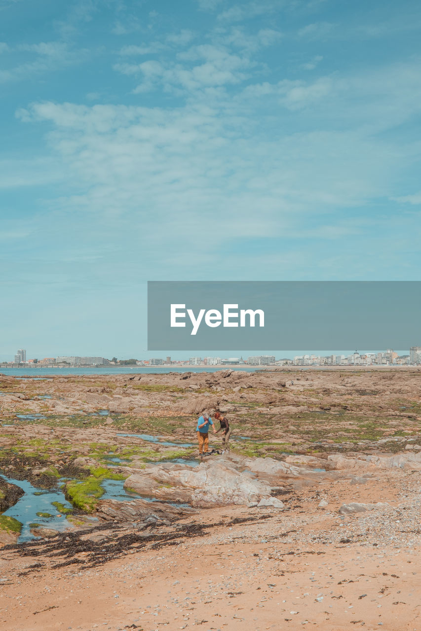 natural environment, sky, landscape, land, nature, sea, day, men, scenics - nature, cloud, environment, full length, coast, horizon, beauty in nature, sand, two people, non-urban scene, blue, lifestyles, leisure activity, shore, tranquility, outdoors, tranquil scene, soil, adult, plain, beach, water