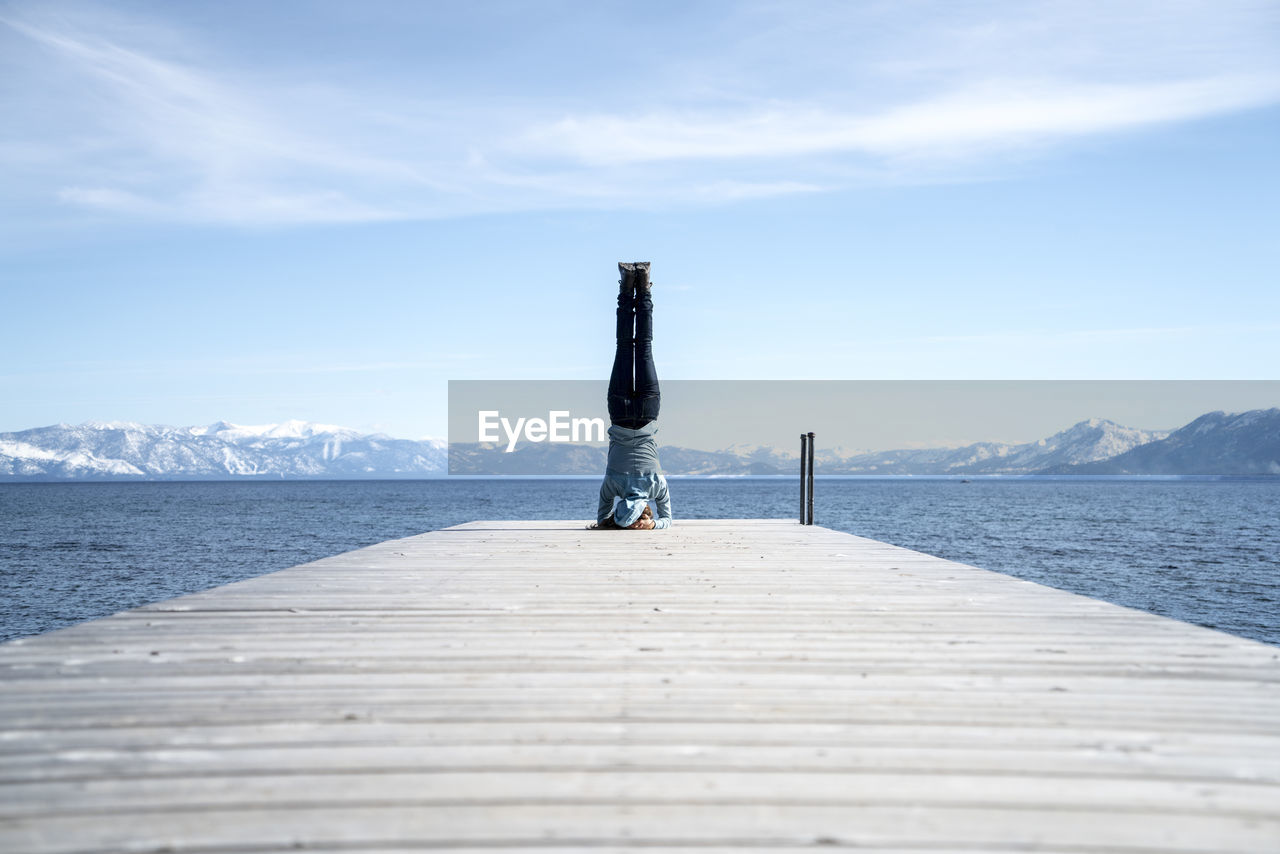 Woman does a headstand at the end of a pier in south lake tahoe, ca