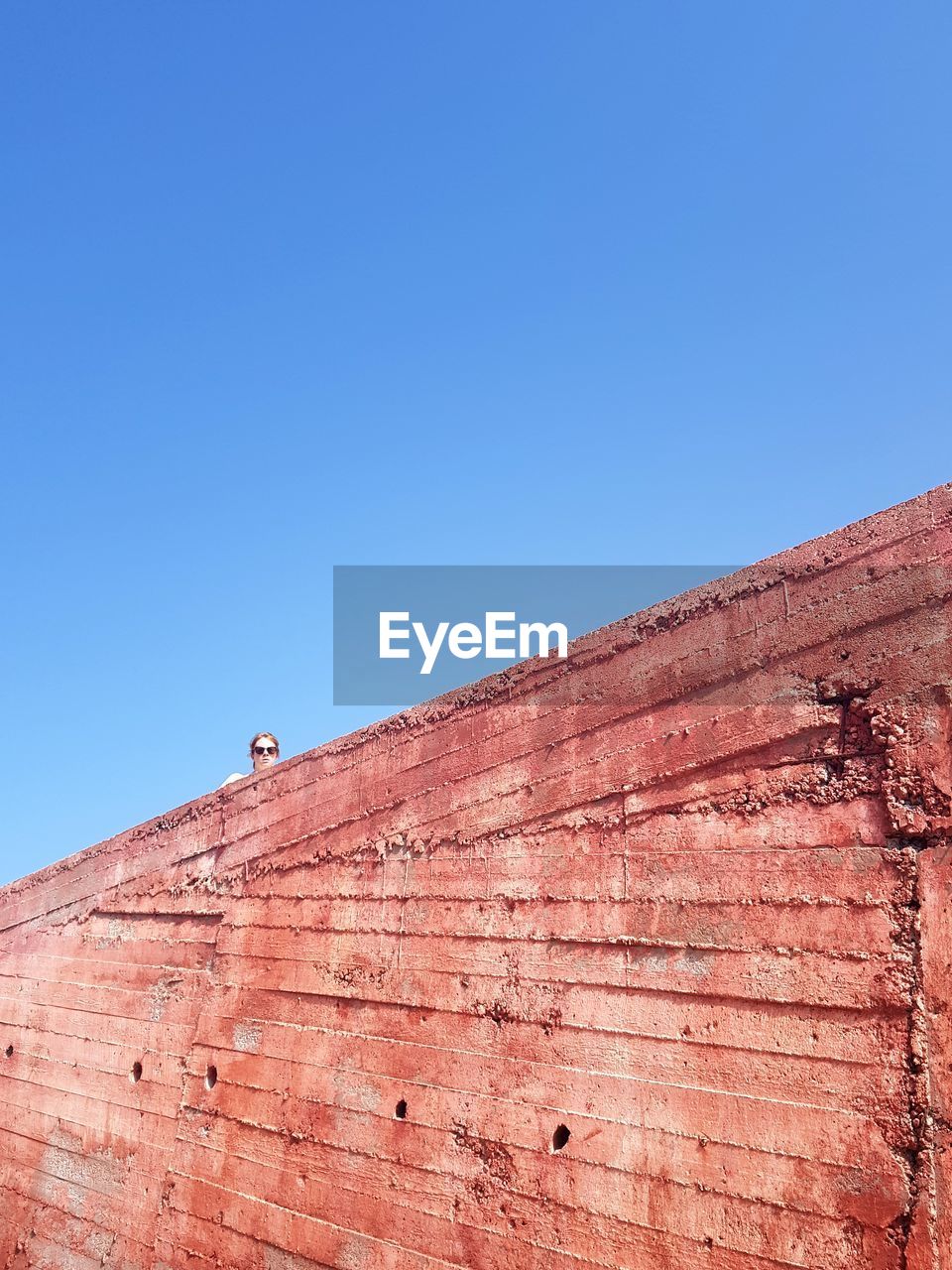 LOW ANGLE VIEW OF WALL AGAINST BLUE SKY