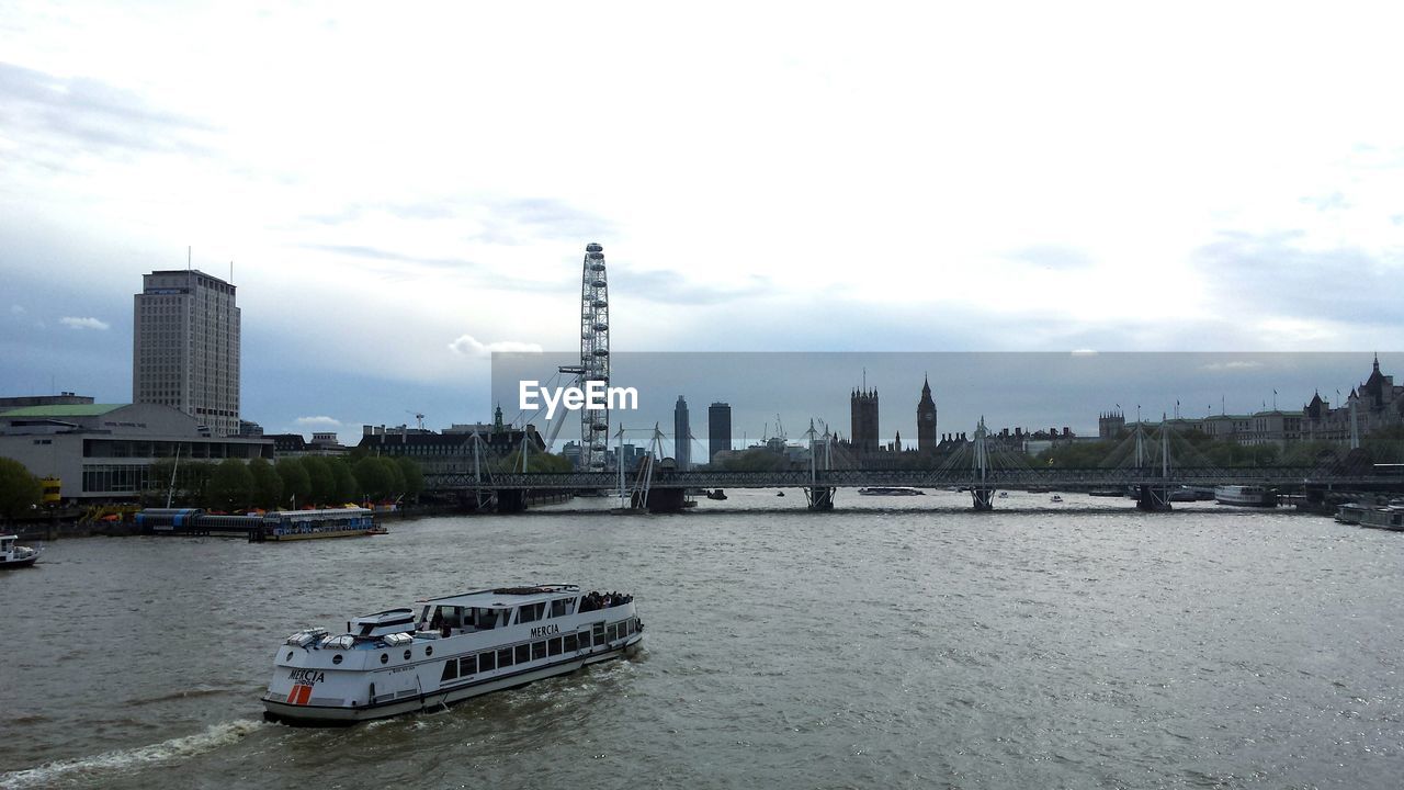 Ferry sailing on thames river by london eye against sky
