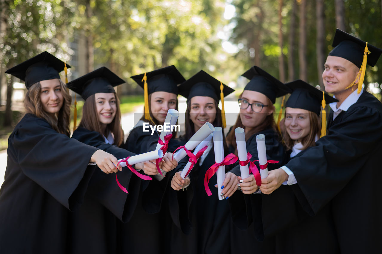 portrait of smiling friends wearing graduation gown