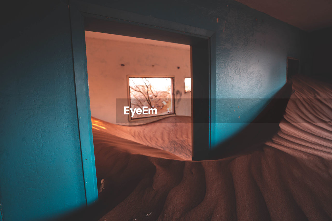 High angle view of open door of house filled with sand