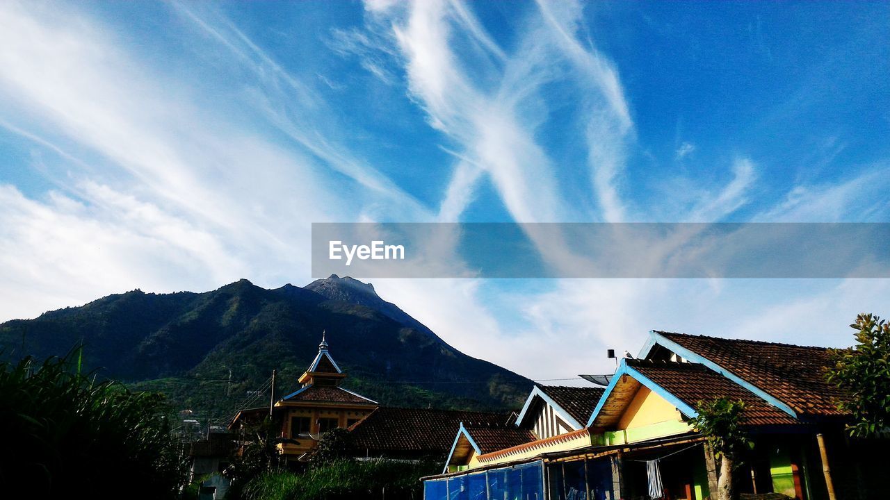 Low angle view of houses and mountains against blue sky