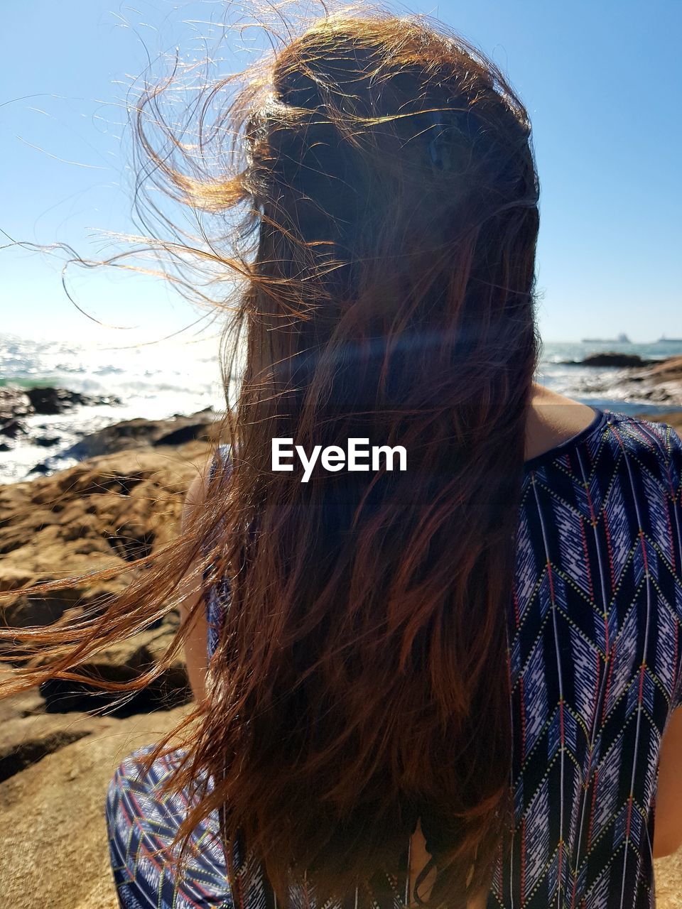 Rear view of woman at beach against sky