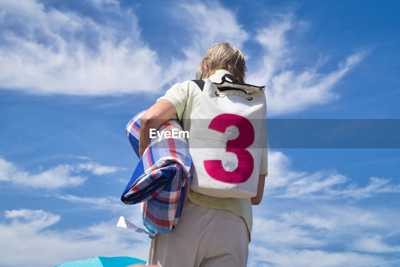 Low angle view of man with backpack against sky