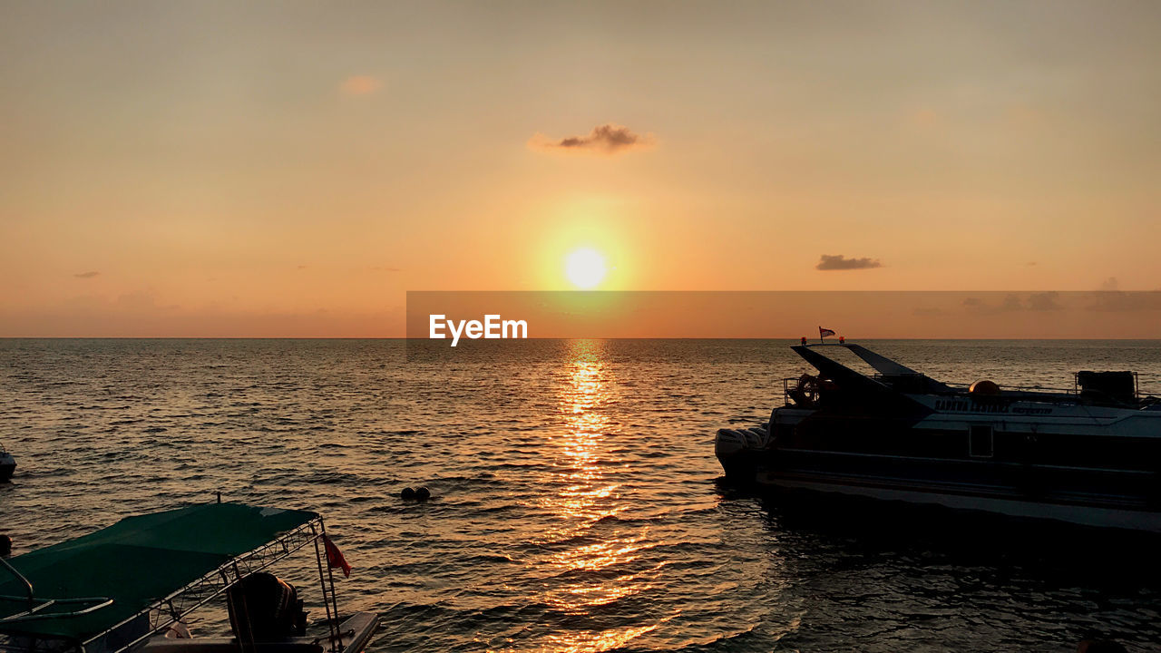 FISHING BOAT IN SEA AGAINST SUNSET SKY