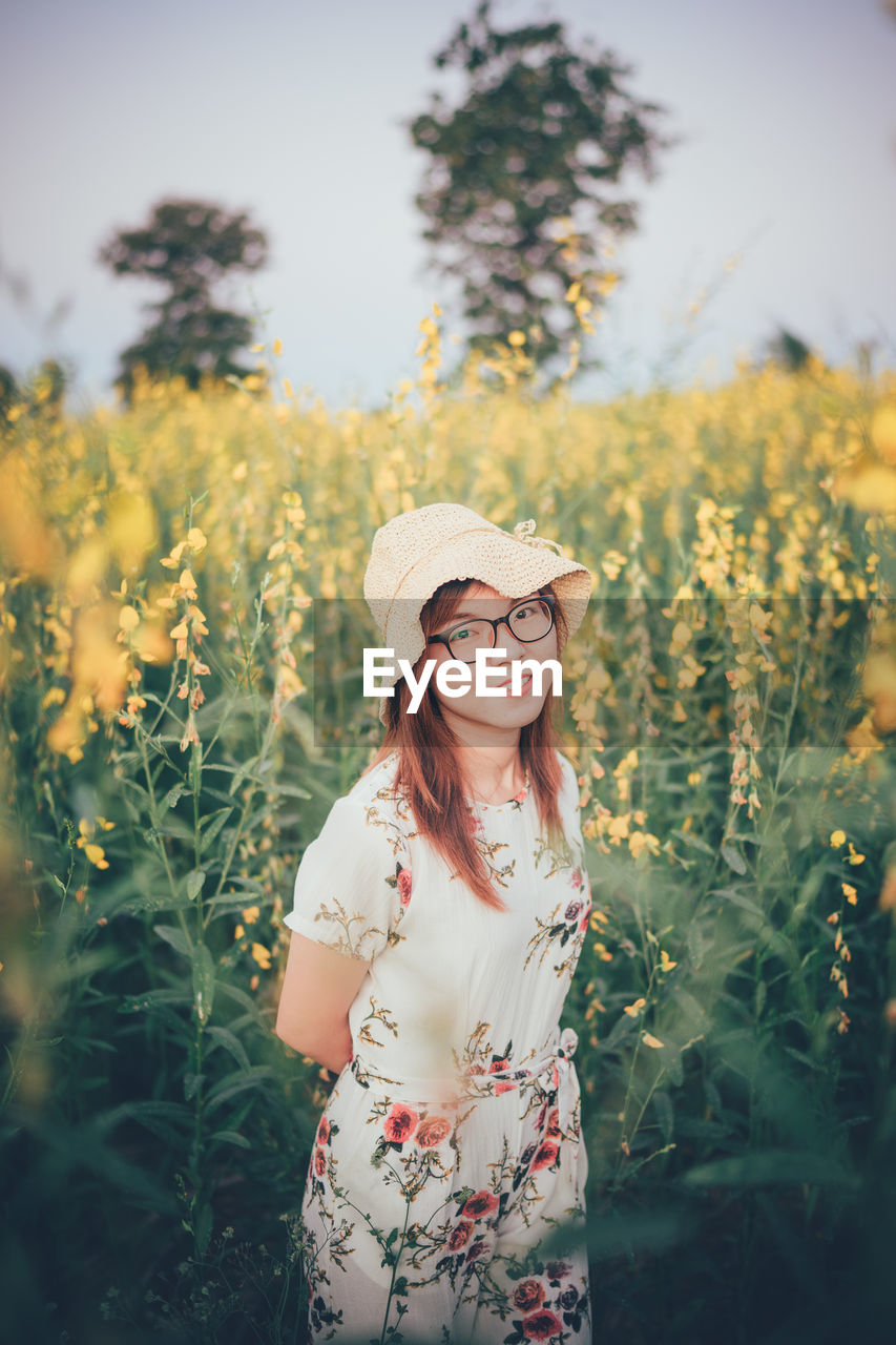 Portrait of smiling woman standing by flowering plants on land