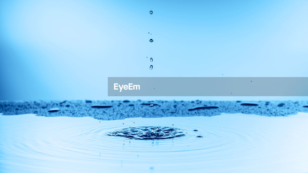 CLOSE-UP OF WATER SPLASHING ON BLUE SEA