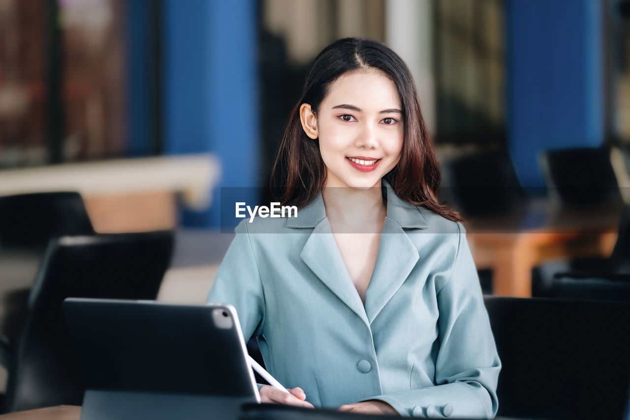 portrait of young woman using laptop while sitting at cafe
