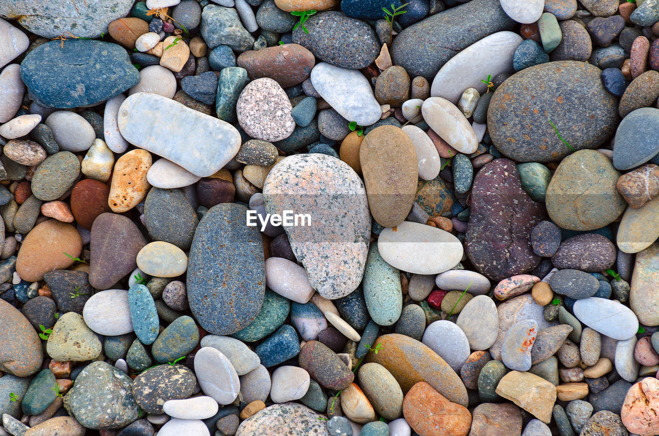 Bright background of multi-colored round stones, sea pebbles close up.