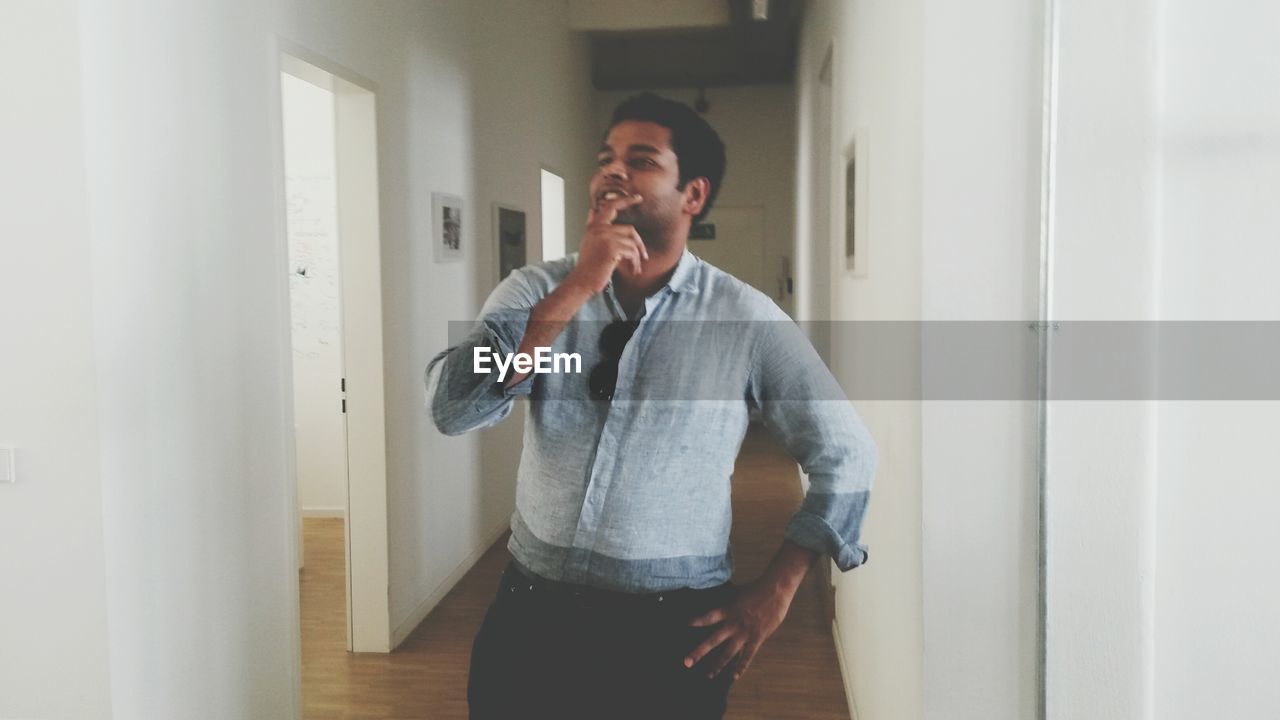 Man thinking while standing in corridor at home