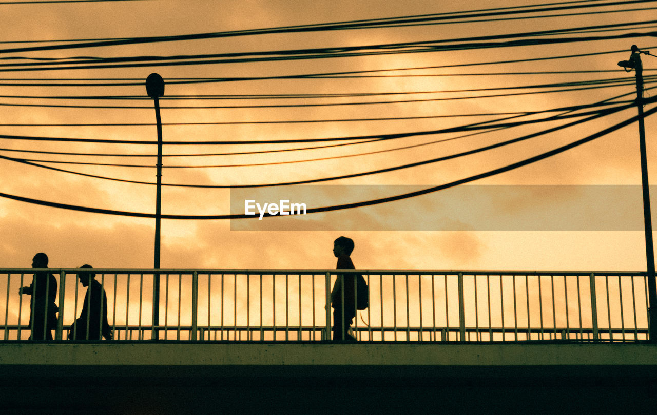 SILHOUETTE PEOPLE STANDING BY RAILING AGAINST SKY DURING SUNSET