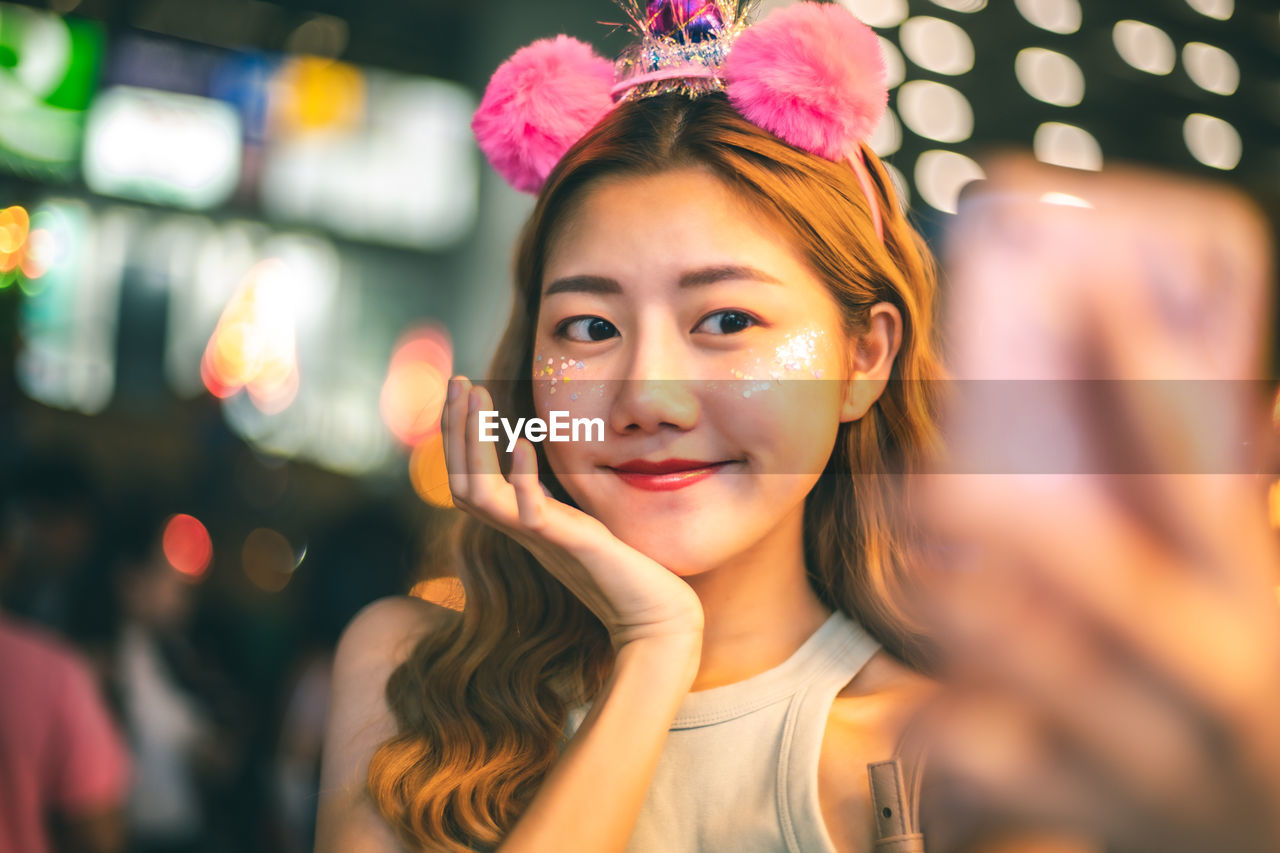 Smiling young woman taking selfie over mobile phone