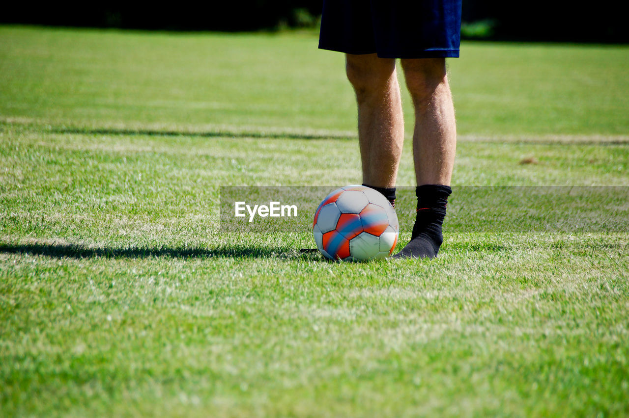 Low section of man playing soccer on grass