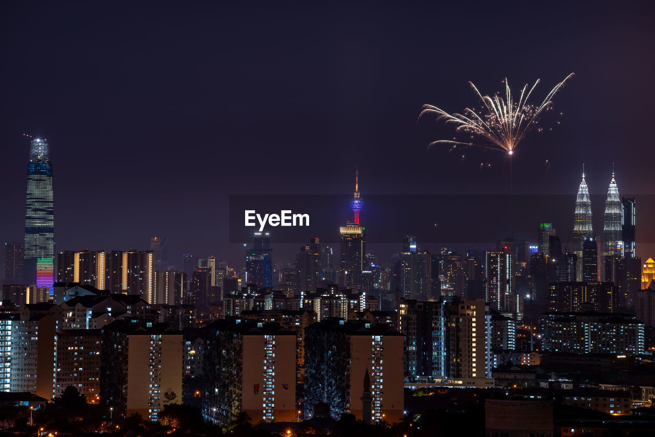 Firework display over illuminated buildings in city at night