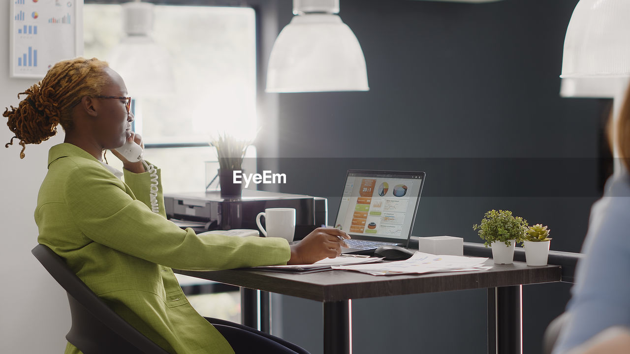 side view of young woman using laptop while sitting at home