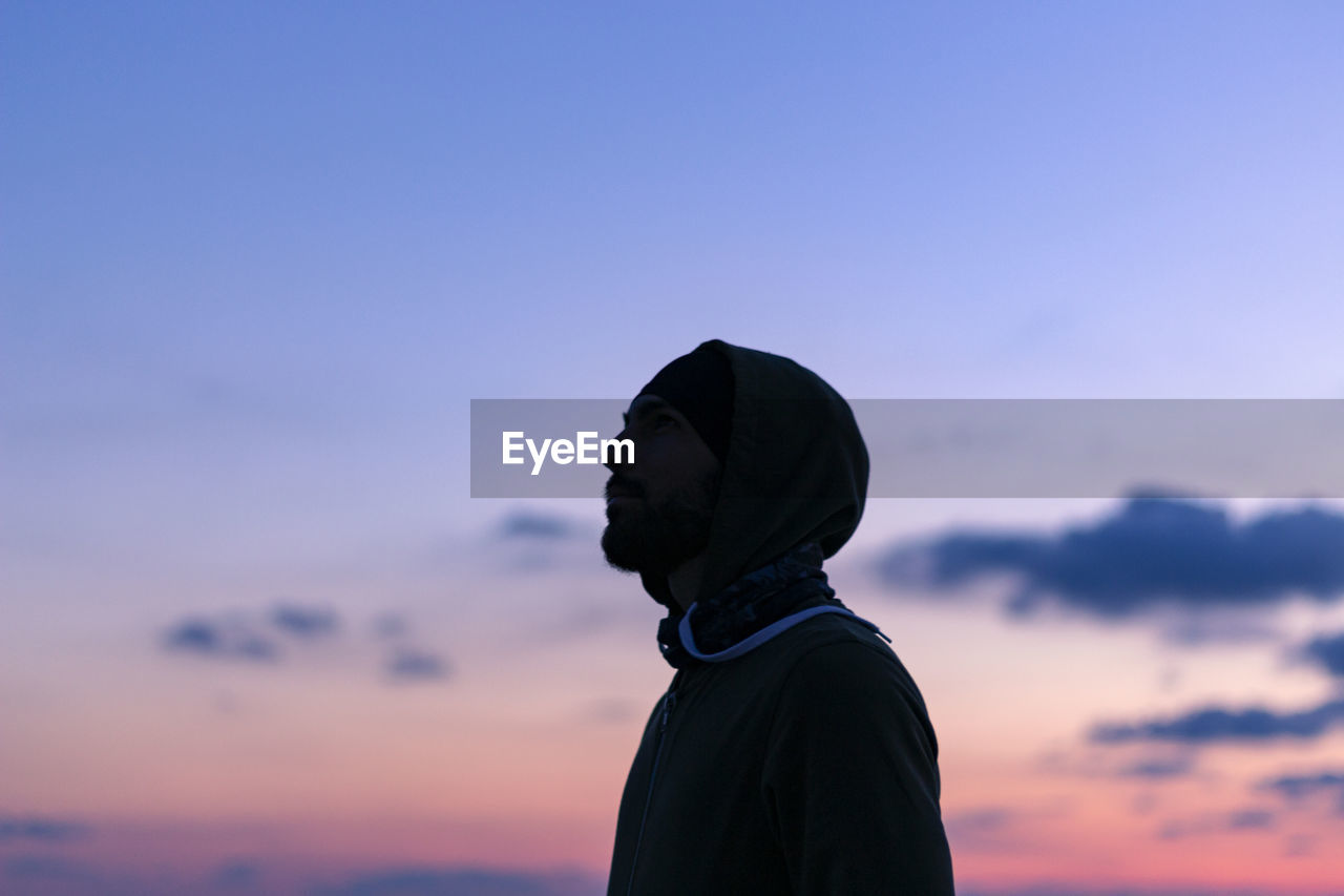 Thoughtful man standing against sky during sunset