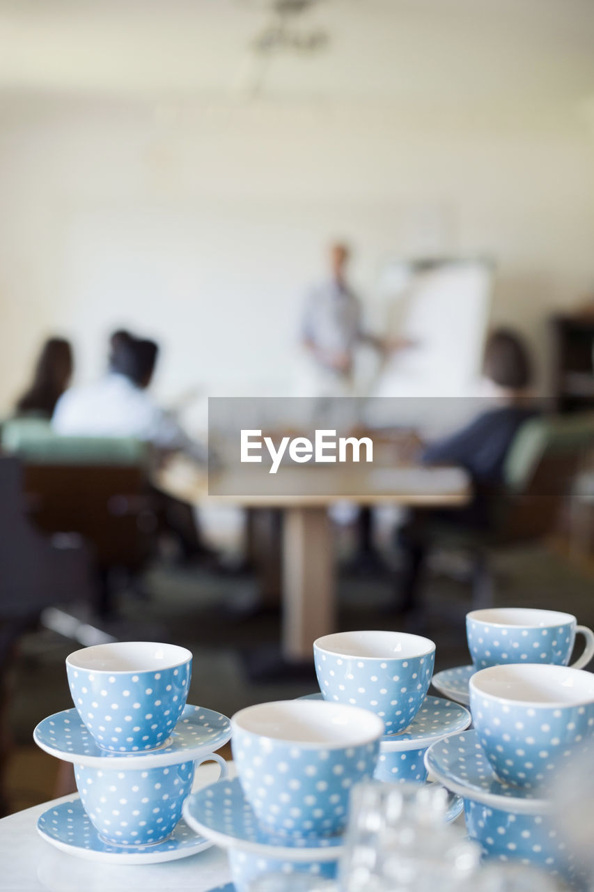 Stacked crockery on table with business people discussing in background