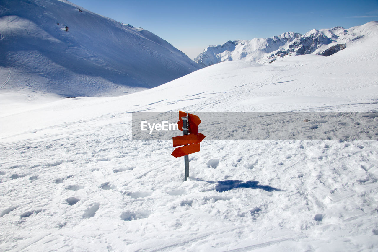 SNOW COVERED FIELD BY MOUNTAIN ROAD