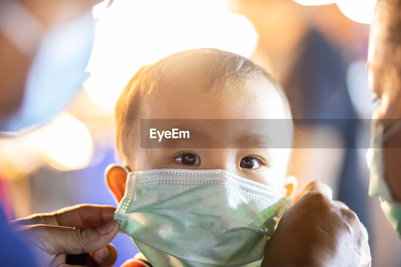 Close-up of parents wearing mask to baby boy