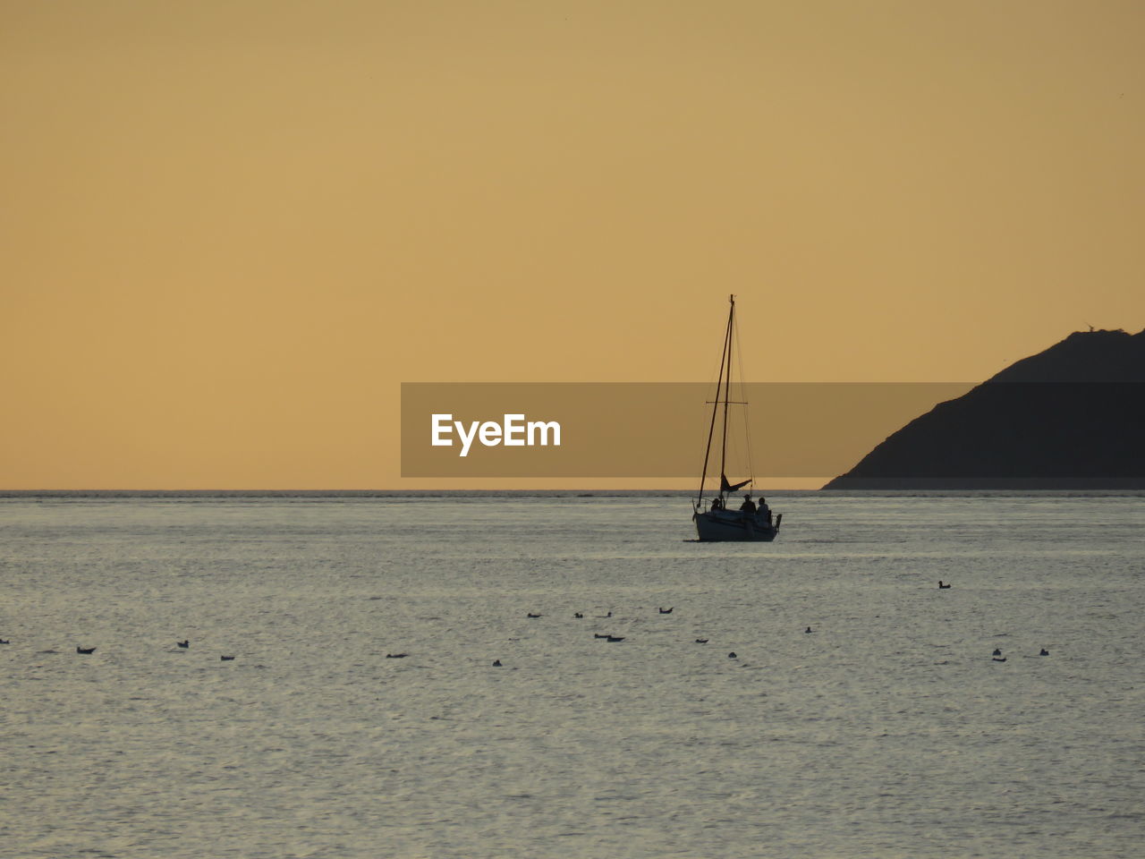 Boat sailing in sea at sunset