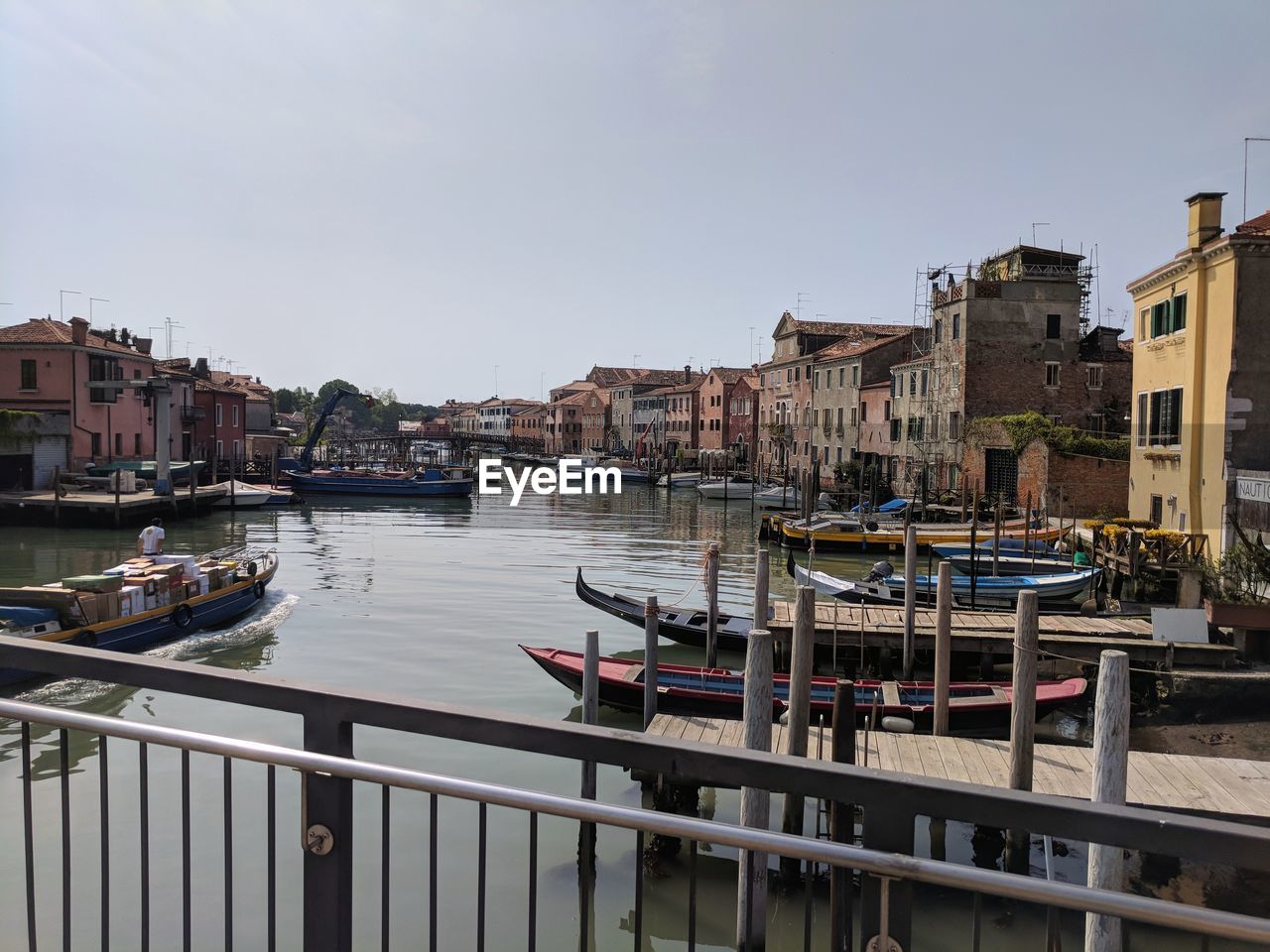 Sailboats moored on canal by buildings in city against clear sky