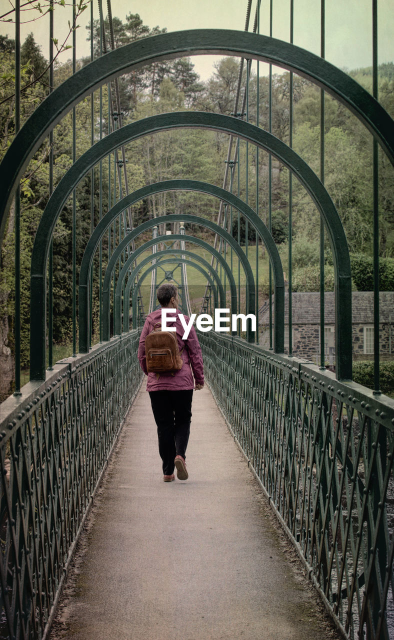 Rear view of woman walking on footbridge