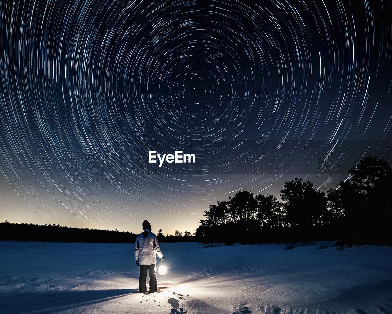 Man standing on snow field against sky at night