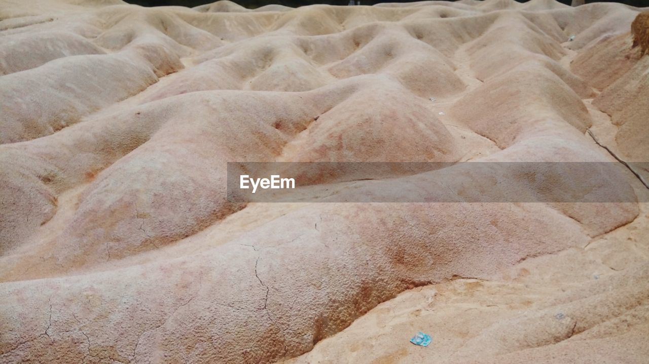 HIGH ANGLE VIEW OF ROCKS ON SAND