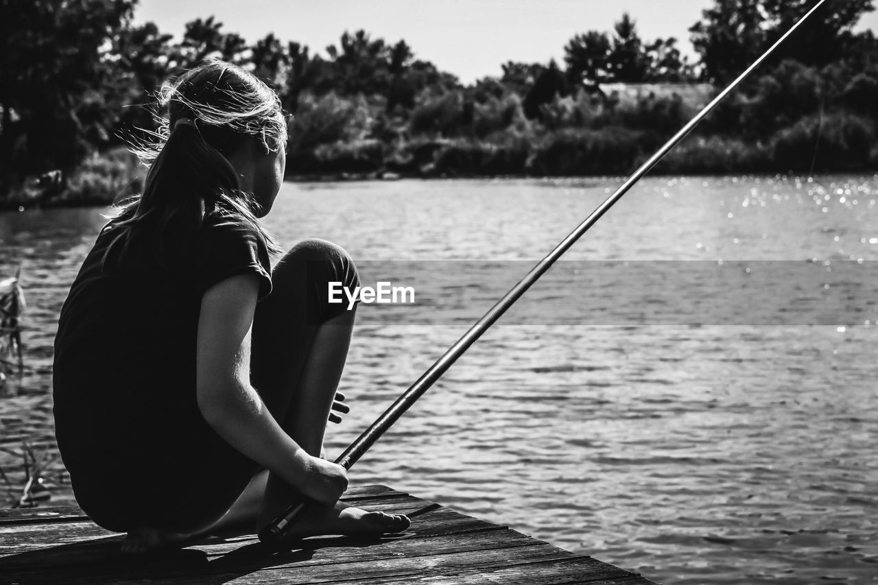 Side view of woman fishing in lake