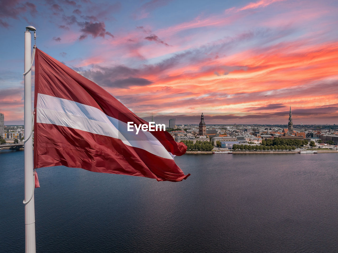 Latvian flag with the dome cathedral and an old town in the background