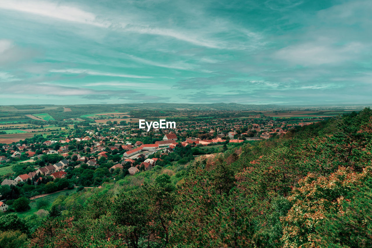 environment, landscape, horizon, sky, nature, cloud, hill, architecture, plant, city, building, land, scenics - nature, building exterior, beauty in nature, morning, residential district, tree, built structure, rural area, aerial photography, no people, green, high angle view, rural scene, field, outdoors, house, grass, town, agriculture, cityscape, leaf, travel destinations, sunlight, flower, dusk, growth, village, tranquility, travel, aerial view, day