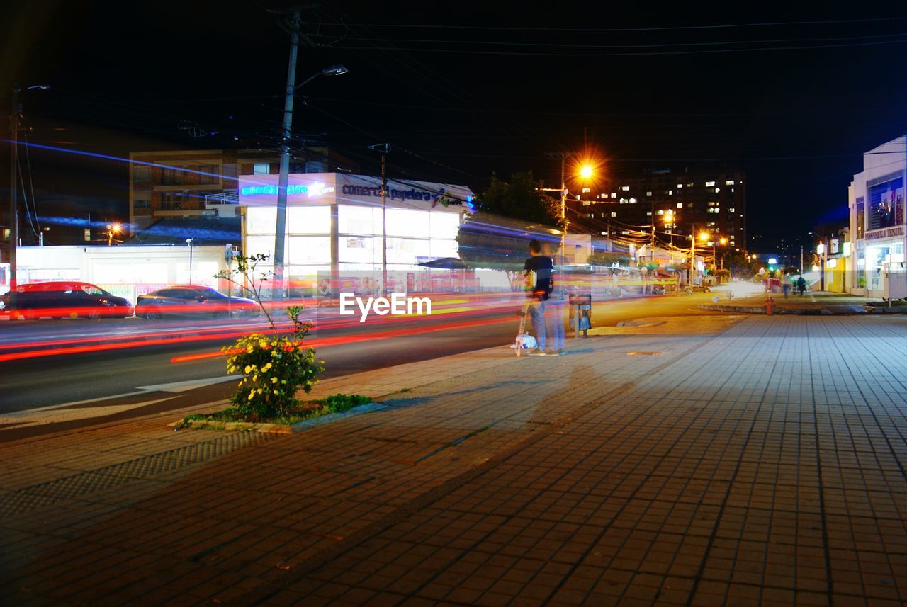 CARS ON ROAD AGAINST ILLUMINATED CITY AT NIGHT