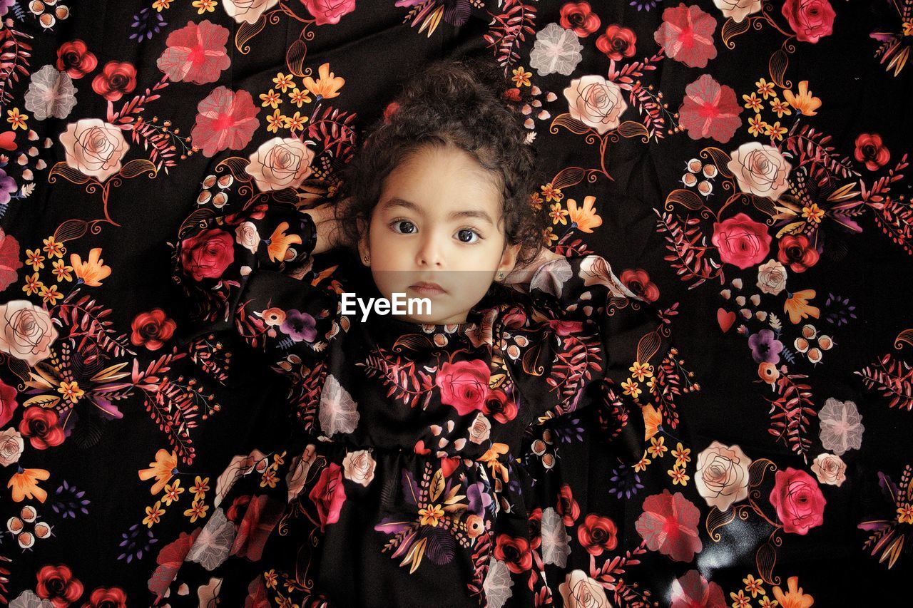 Portrait of cute girl against floral curtain