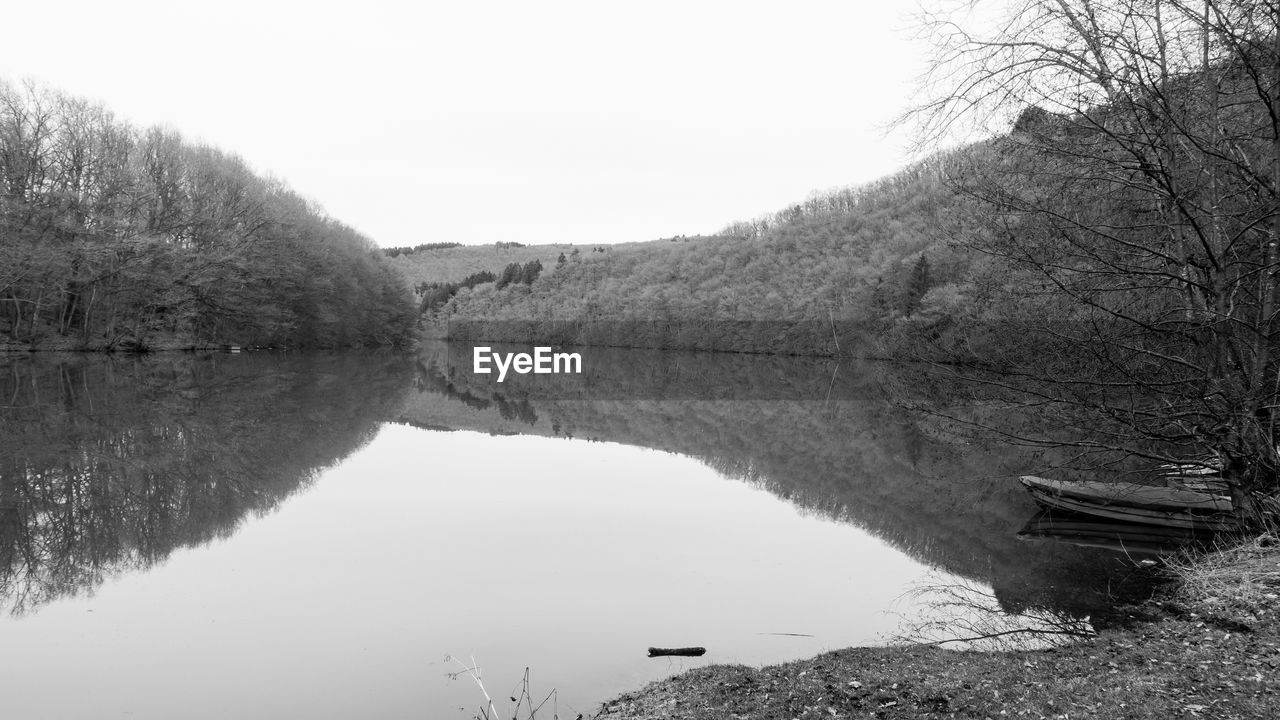 REFLECTION OF TREES IN LAKE AGAINST SKY