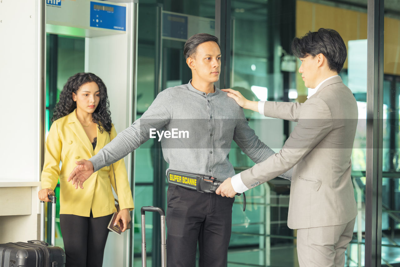 In the airport, people are going through the physical screening and luggage scanning procedures.