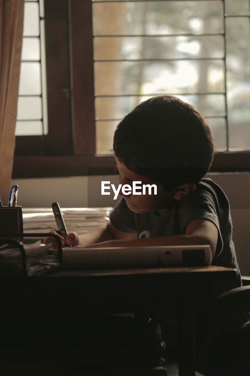 Boy sitting studying on table at home
