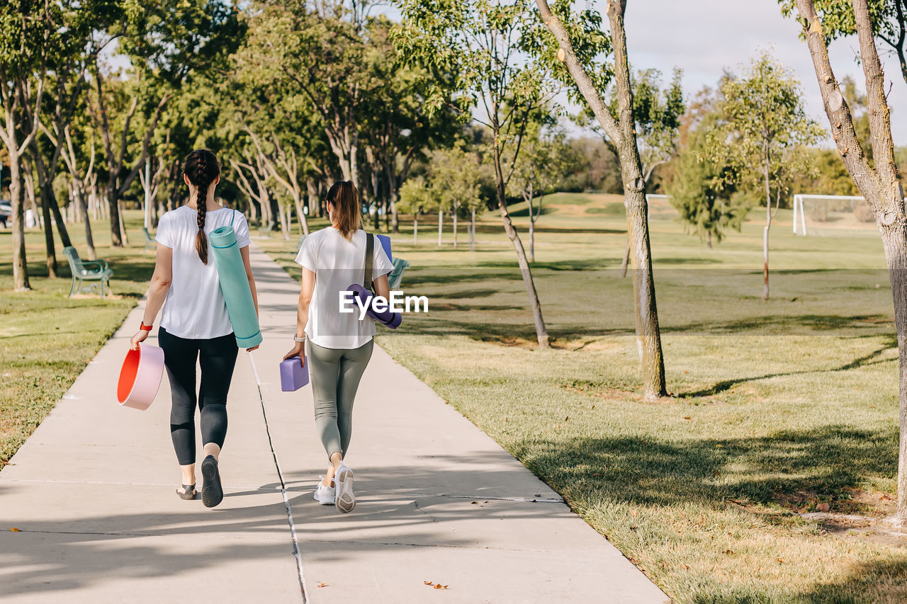 Two young women walking in the morning park, going to exercise outdoors.